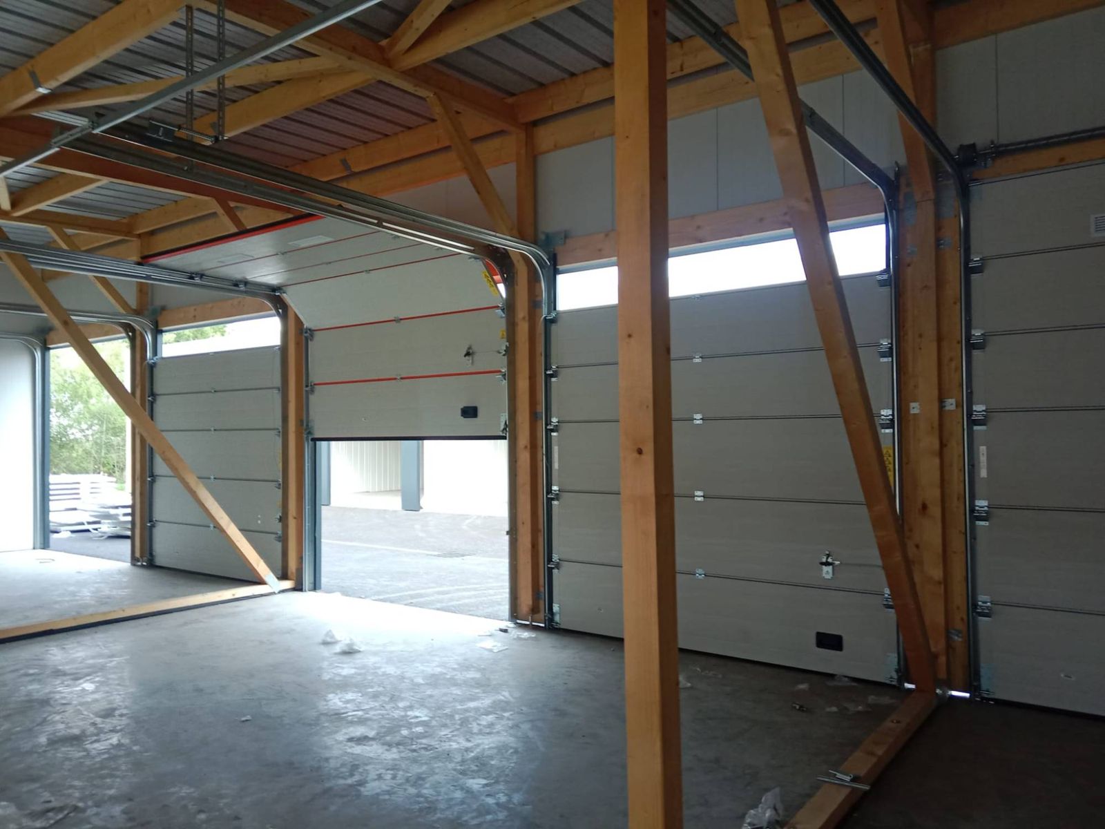 Portes sectionnelles industrielles posées dans des cellules d’activité à charpente bois